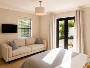 Ein Schlafzimmer mit einem Bett, einem Sofa, einem Fernseher und einem Fenster mit Jalousien.