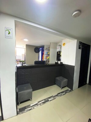 A reception area with a counter, a small seating area, and a wall-mounted clock. - 33hotel (Medellín)