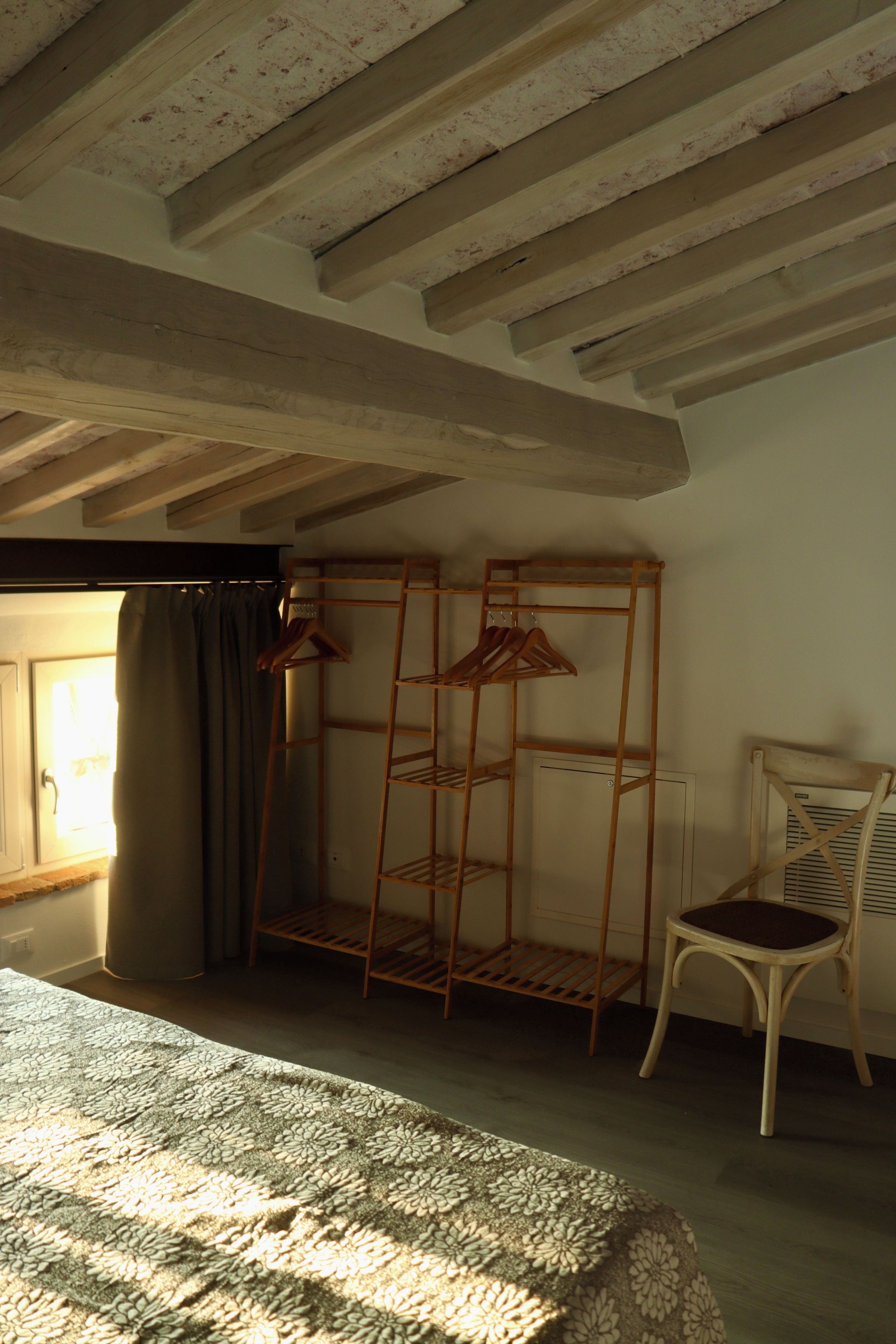 Une pièce avec une chaise en bois, un étagère en métal et un tapis à motifs.