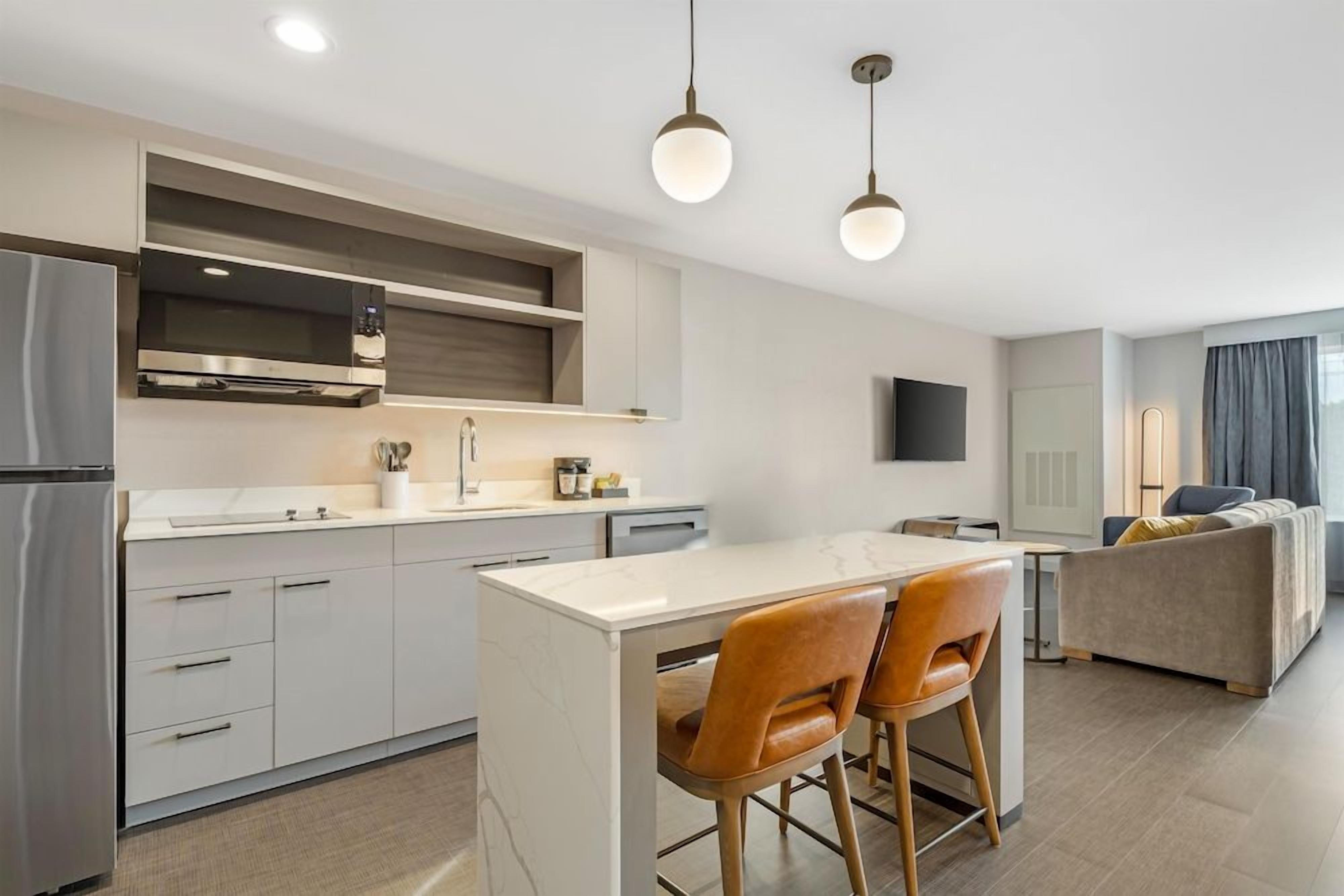 Une cuisine moderne dotée d’un îlot central, de tabourets de bar et de luminaires suspendus.
