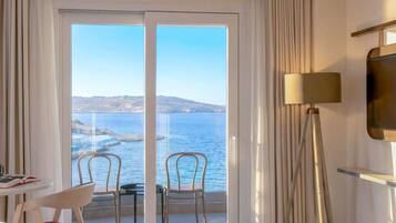 A hotel room with a large sliding glass door leading to a balcony with a view of the sea.