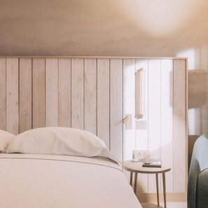 Un dormitorio con pared de paneles de madera, cama con ropa blanca, mesita de noche con lámpara y una silla.