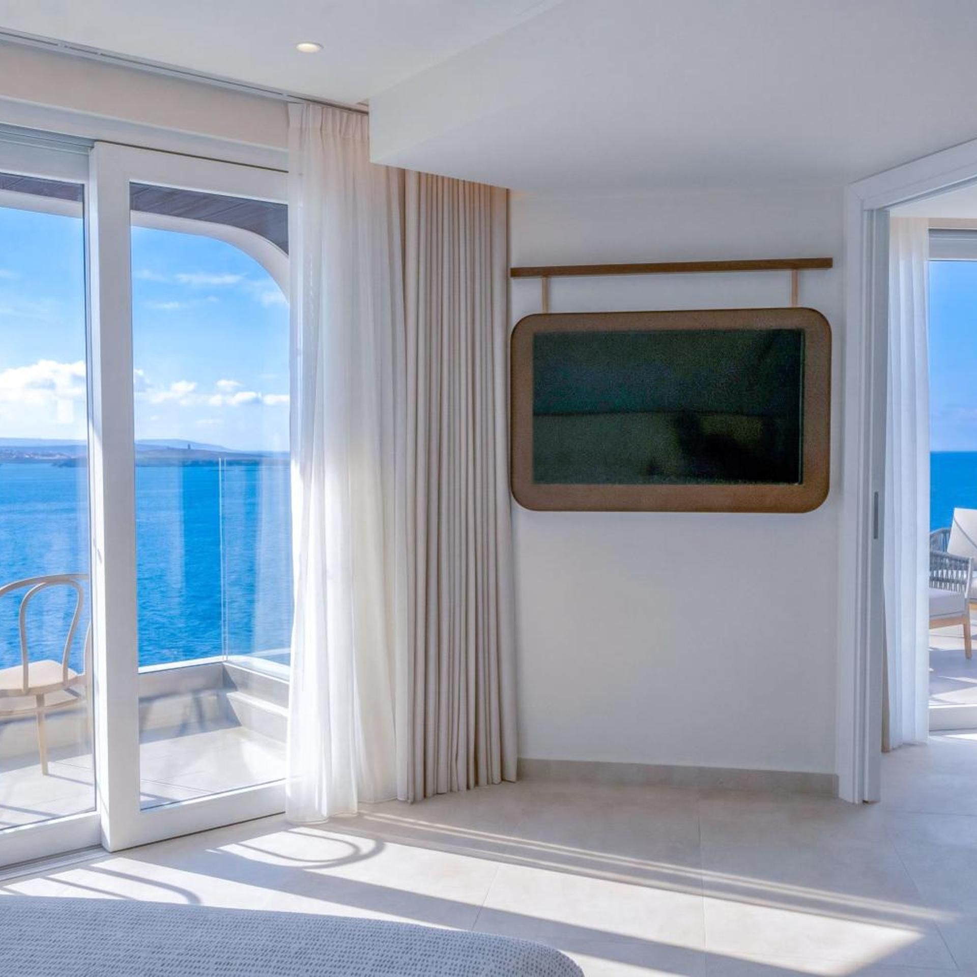 Una habitación con un ventanal grande, una puerta que da a un espacio exterior y una pantalla montada.
