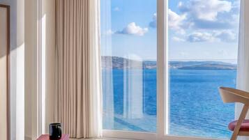 Una habitación moderna con un amplio ventanal corredero que da a un balcón con vistas al mar.