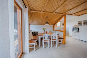 Una cocina moderna con armarios blancos, una mesa de comedor de madera y un amplio ventanal.