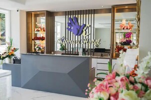Un mostrador de recepción con un logotipo, un arreglo floral y un espejo.