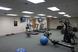 Academia com esteiras, elípticos e bolas de exercício.