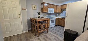 Une cuisine compacte avec des meubles en bois, un réfrigérateur blanc et une table à manger avec des chaises.