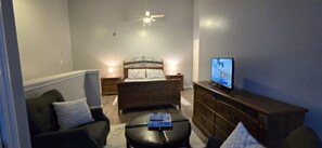 Une chambre à coucher avec un lit, des tables de chevet, une télévision et un canapé.