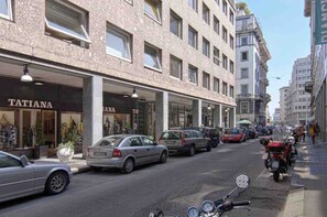 Vista d'un carrer amb cotxes aparcats i un edifici amb el rètol 'TATIANA'.
