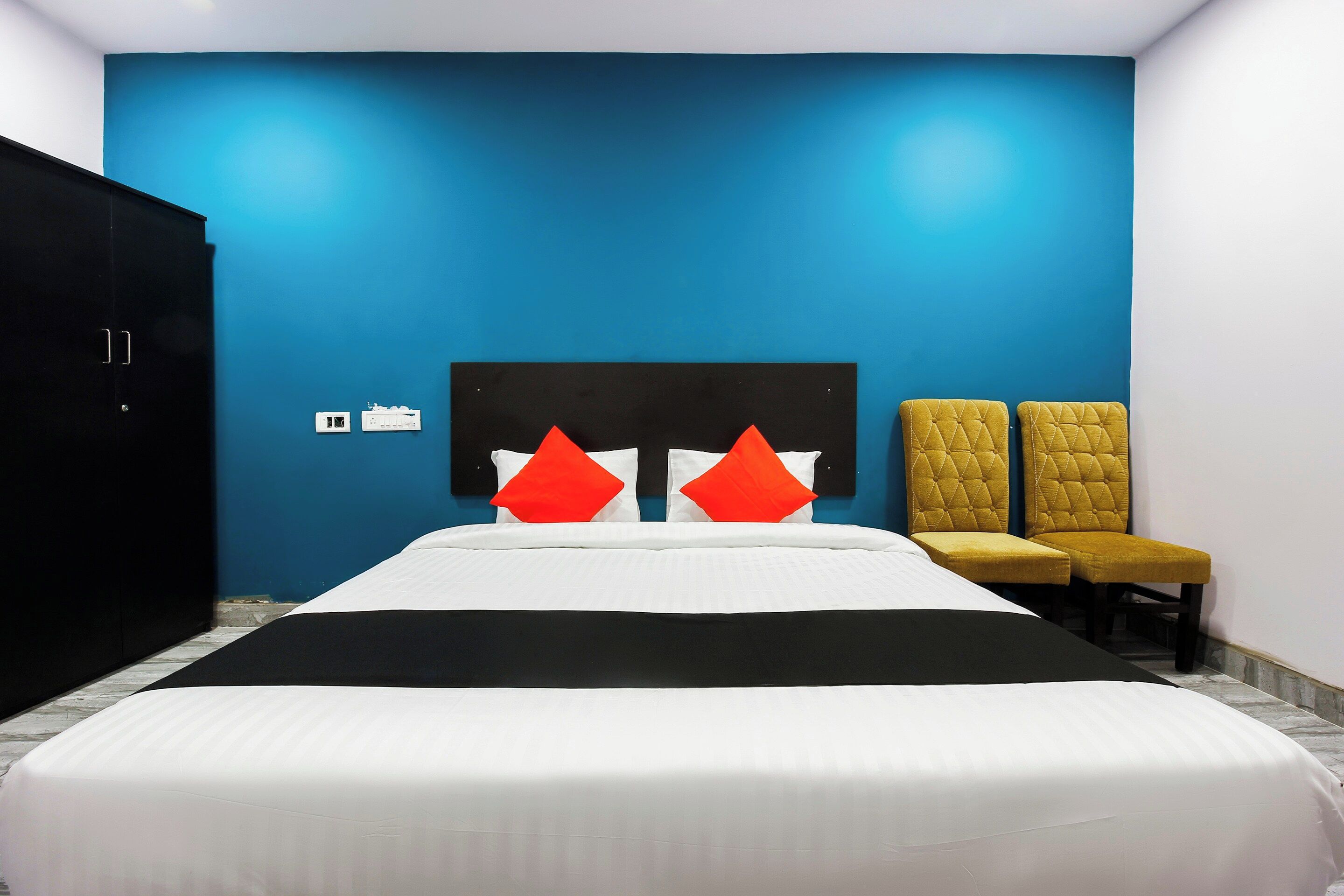 Ein Hotelzimmer mit einem Bett, zwei Stühlen, einem Kleiderschrank und einer Wand mit Steckdose.