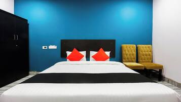 Ein Hotelzimmer mit einem Bett, zwei Stühlen, einem Kleiderschrank und einer Wand mit Steckdose.