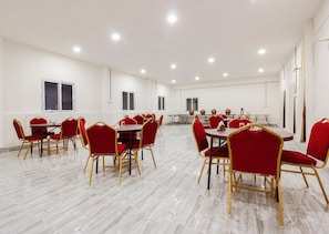 A spacious conference room with multiple tables and chairs, white walls, and a marble floor.