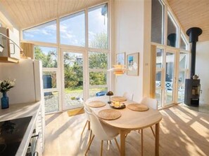 A modern interior with a dining area, large windows, and a fireplace. - "Herdina" - 300m from the sea by Interhome (Grenaa)