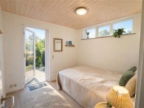 A bedroom with a bed, a window, a door, and a small table with a lamp. - "Herdina" - 300m from the sea by Interhome (Grenaa)
