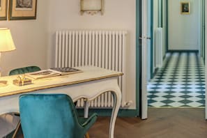 Une pièce avec un bureau, une chaise, un radiateur et un sol à carreaux.