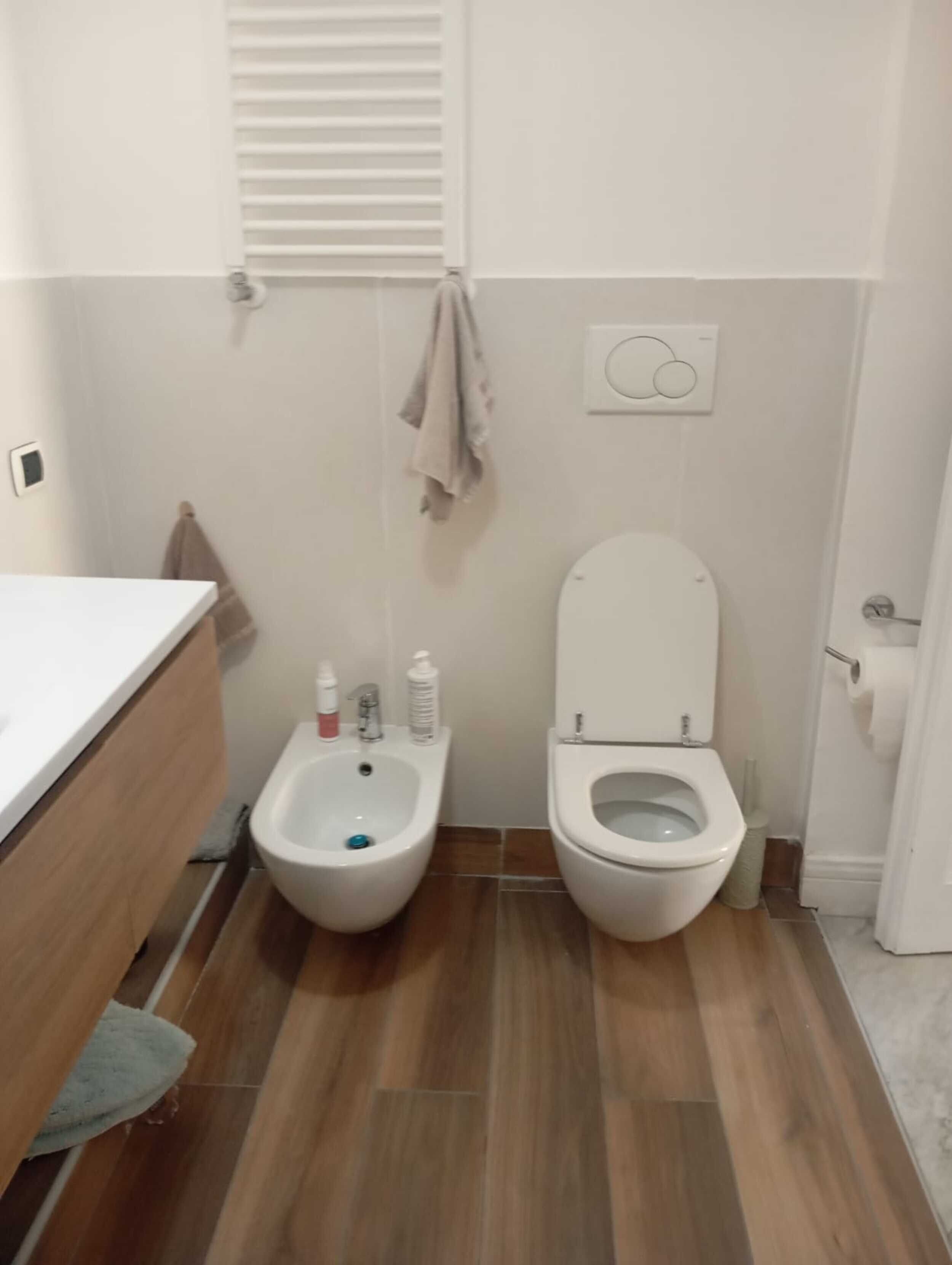 A bathroom with a bidet, toilet, and a towel hanging on the wall.