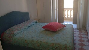 Ein Schlafzimmer mit einem Bett, einem Nachttisch und Blick auf den Balkon.