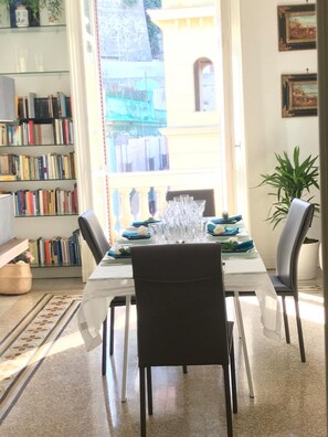 Ein Essbereich mit einem Tisch für vier Personen, einem Bücherregal und Blick auf ein Gebäude.