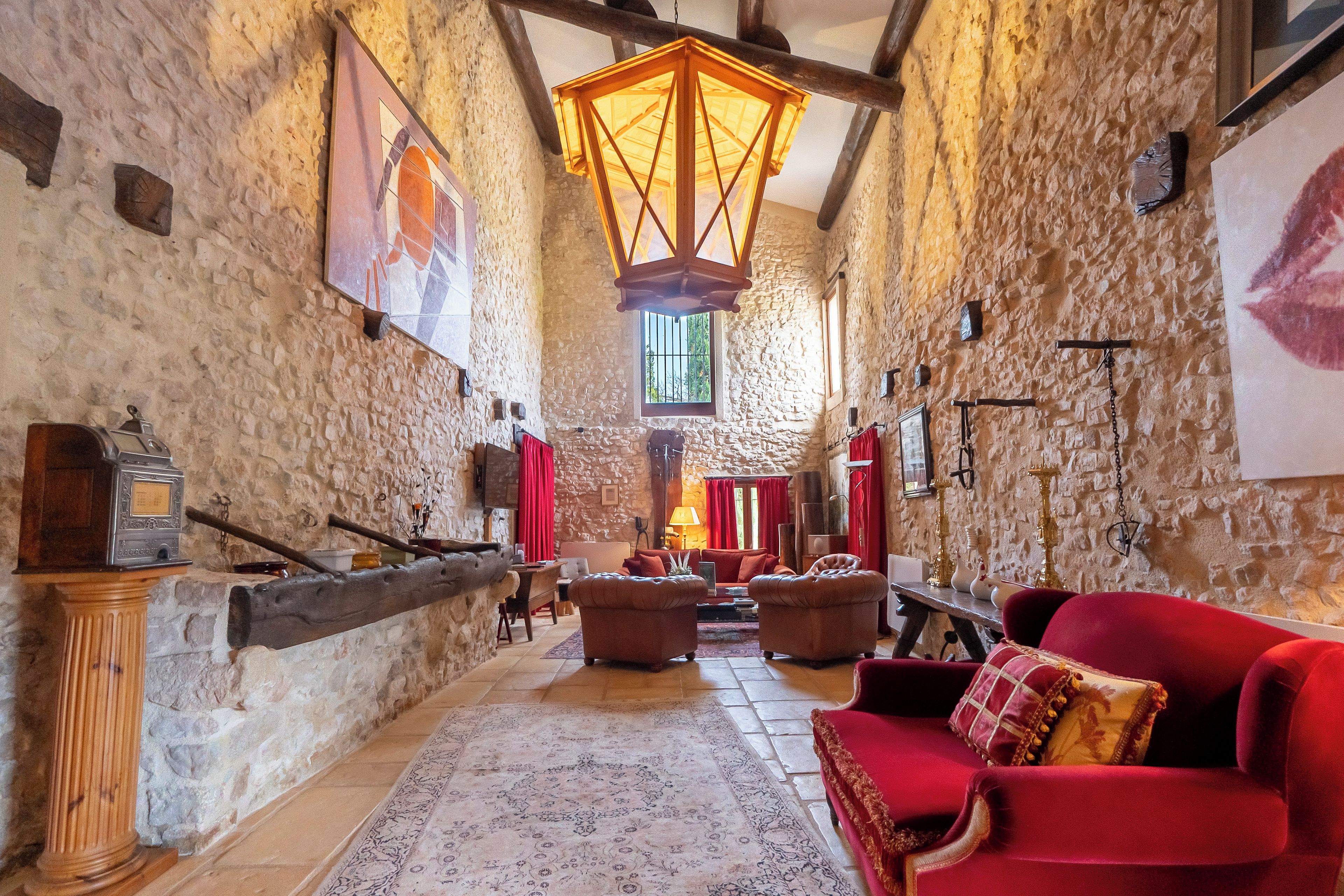 A spacious interior with stone walls, a wooden ceiling, and a red sofa.
