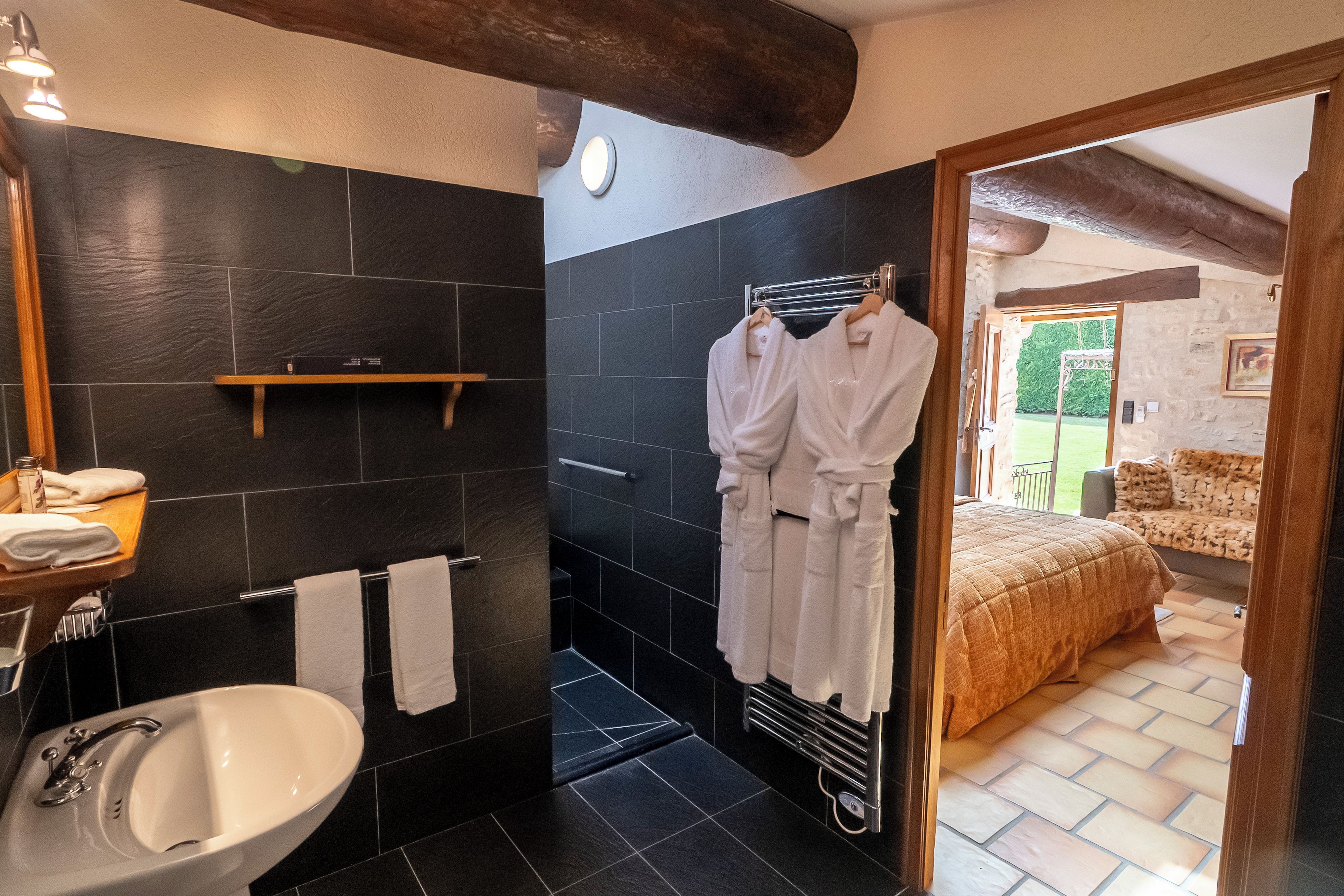 A bathroom with a sink, towel rack, and dark tiled walls.
