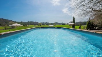 A clear swimming pool with a view of a green landscape and trees in the background.