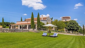 A villa with a stone wall, a covered patio, and a lawn with lounge chairs. - La Tour d'Enguerne (Montmeyan)