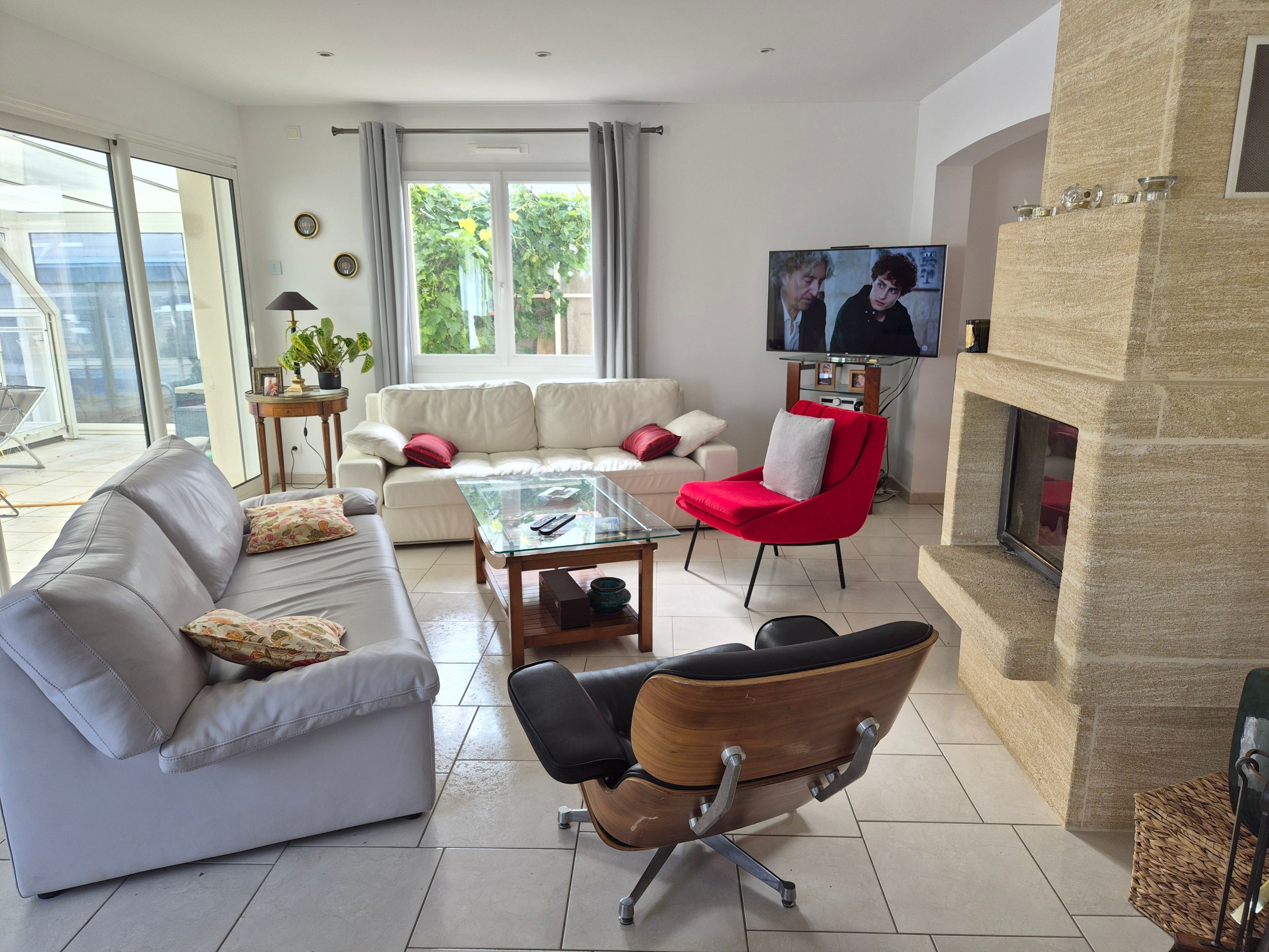 A living room with a sofa, armchairs, a coffee table, and a television.