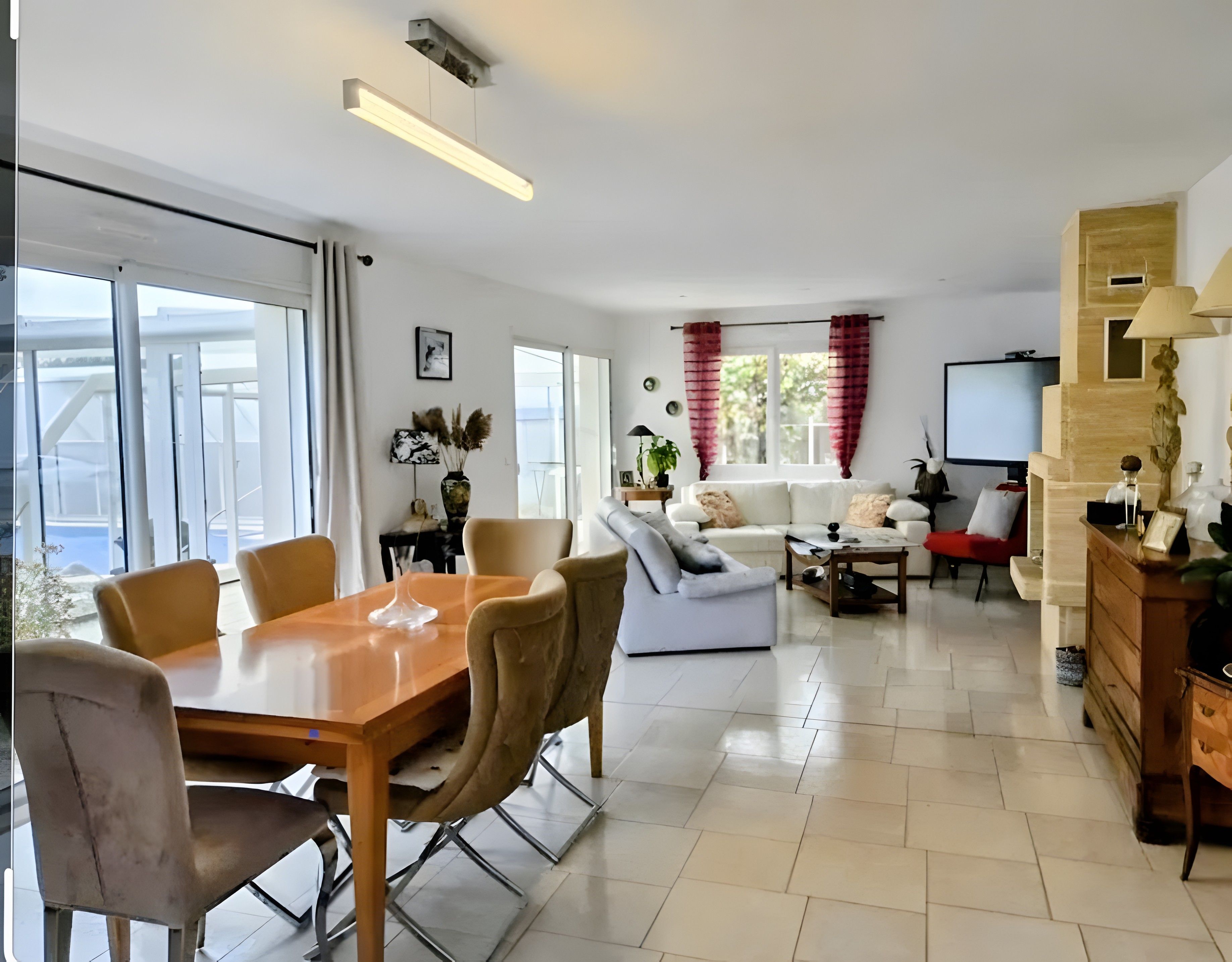 Een moderne woonkamer met een eethoek, witte banken, een salontafel en een televisie.