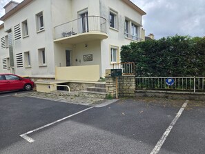 Um edifício residencial de vários andares com varanda, caixa de correio e placa de estacionamento.