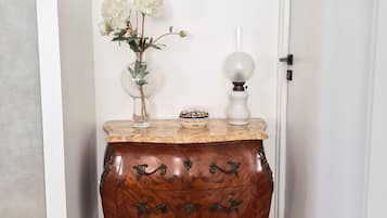 Una mesita de madera con un florero y una lámpara frente a una pared blanca.