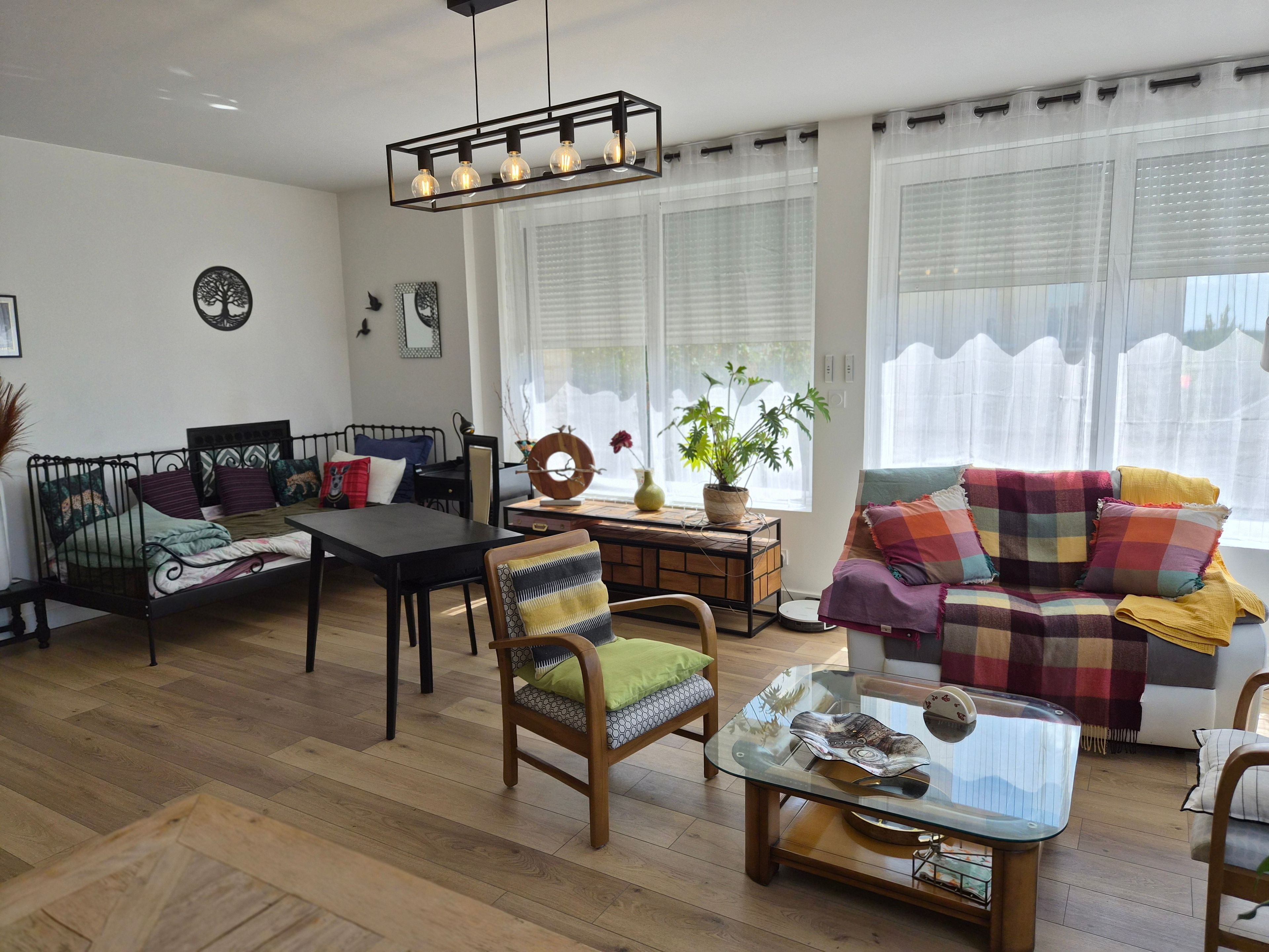 A living room with a sofa, a table, a chair, and a bed.