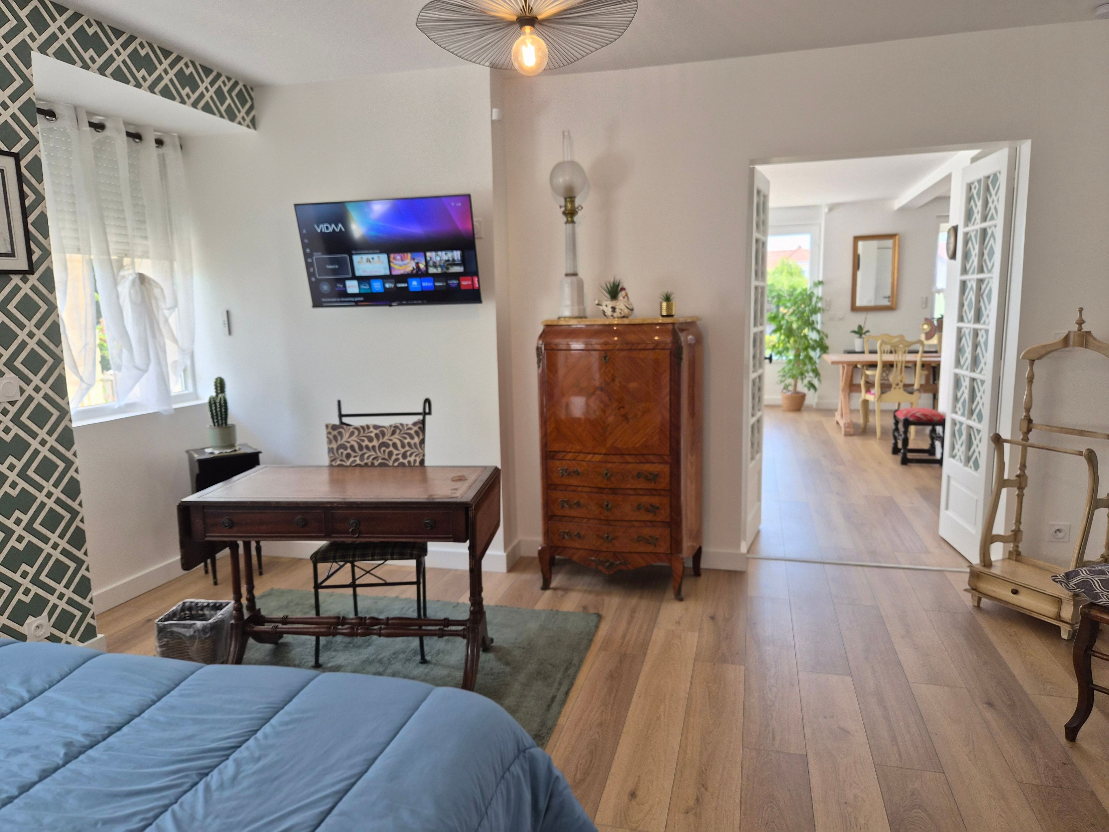 A bedroom with a bed, a desk, a television, and a wardrobe.