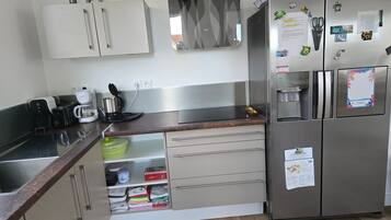 Una cucina moderna con elettrodomestici in acciaio inossidabile, forno integrato e macchina per il caffè.