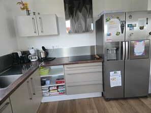Cozinha moderna com eletrodomésticos de aço inoxidável, forno embutido e cafeteira.
