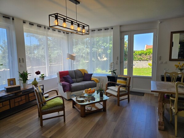 Uma sala de estar moderna com sofá, cadeiras, mesa de centro e área de jantar.