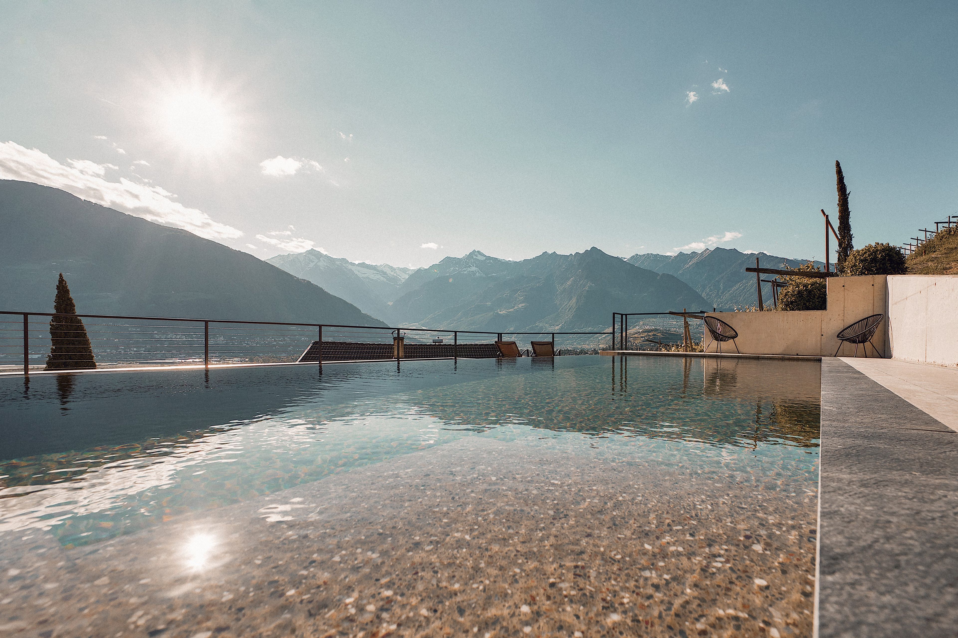 An infinity pool with a clear view of a mountain range and a body of water.