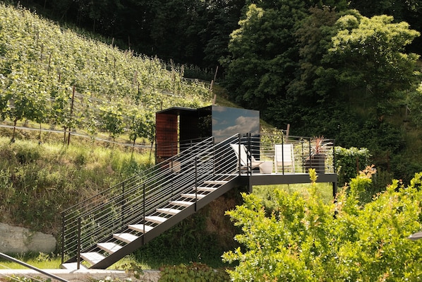 Un escalier menant à une zone abritée d’où l’on peut admirer une colline boisée.