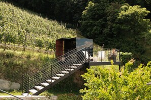 Una scala conduce a una zona coperta da cui si può ammirare una collina ricoperta di bosco.