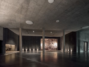 Un intérieur spacieux avec un plafond haut, des murs en béton et un élément décoratif central en pierre.