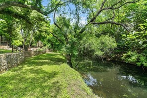 A serene riverside pathway with a stone wall and lush greenery. - Cozy 1BR retreat with king bed, WiFi, fire pit, and walkable Fredericksburg charm. (Fredericksburg)