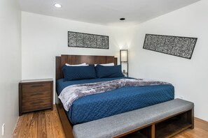 Ein Schlafzimmer mit einem Bett, einem Nachttisch, einer Bank und zwei Wandleuchten.