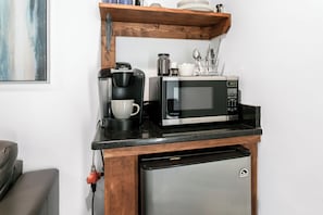 Een kleine keuken met een koffiezetapparaat, magnetron en vaatwasser.