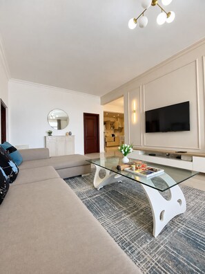A modern living room with a glass coffee table, a flat-screen TV, and a sofa. - Spacious and modern 2-bedroom apartment in Central Osu, Chateau Apartments (Accra)