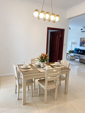 A dining area with a table set for four, a vase of flowers, and a modern chandelier. - Spacious and modern 2-bedroom apartment in Central Osu, Chateau Apartments (Accra)