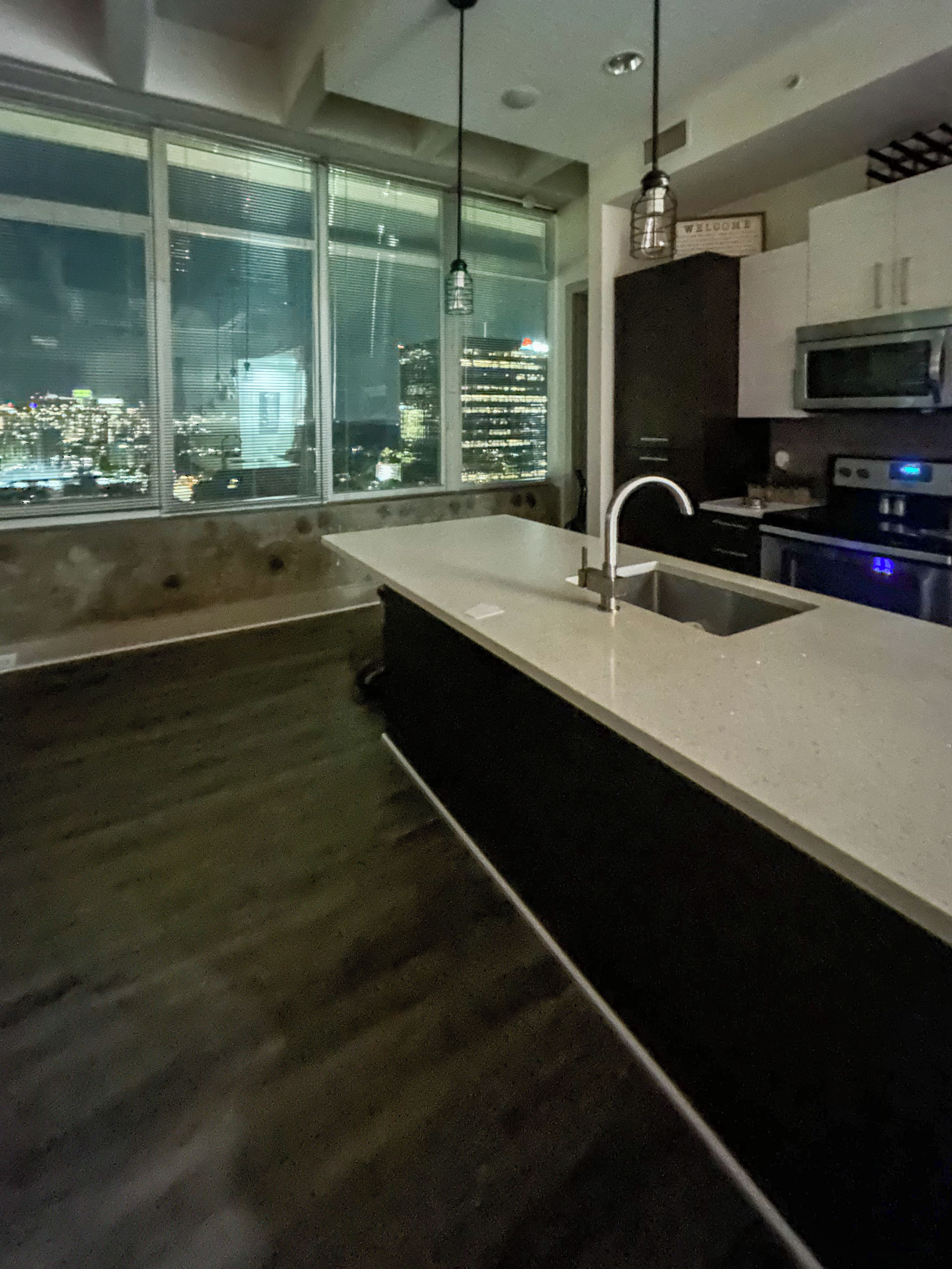 Una cocina moderna con un ventanal grande, un microondas integrado y un lavamanos de acero inoxidable.