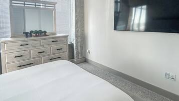 Un dormitorio con una cama grande, un aparador, un espejo y un televisor de pantalla plana montado en la pared.