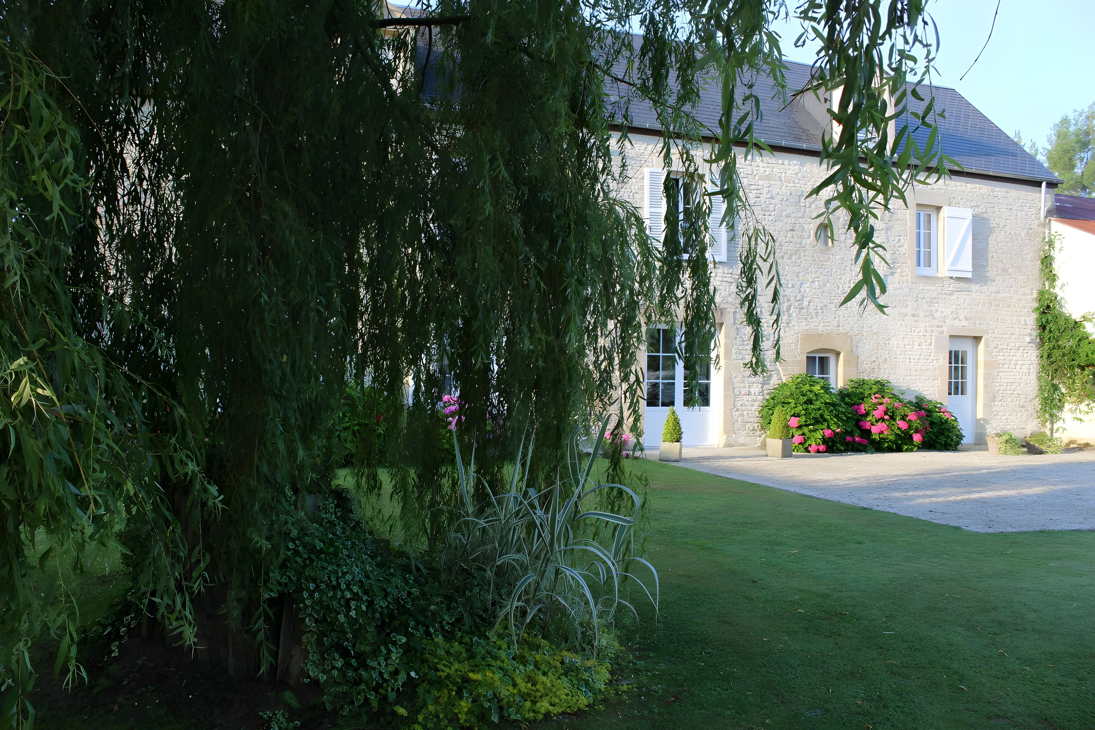 A stone building with a paved driveway and a well-maintained lawn.