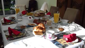 Een ontbijttafel gedekt met diverse producten, waaronder croissants, fruit en drankjes.