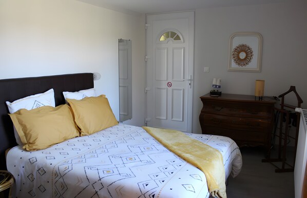 A bedroom with a bed, a dresser, a door, and a wall-mounted mirror. - Bed and Breakfast 'Entre Mer Et Terre - Chambre' with Shared Garden and Wi-Fi (Bazenville)